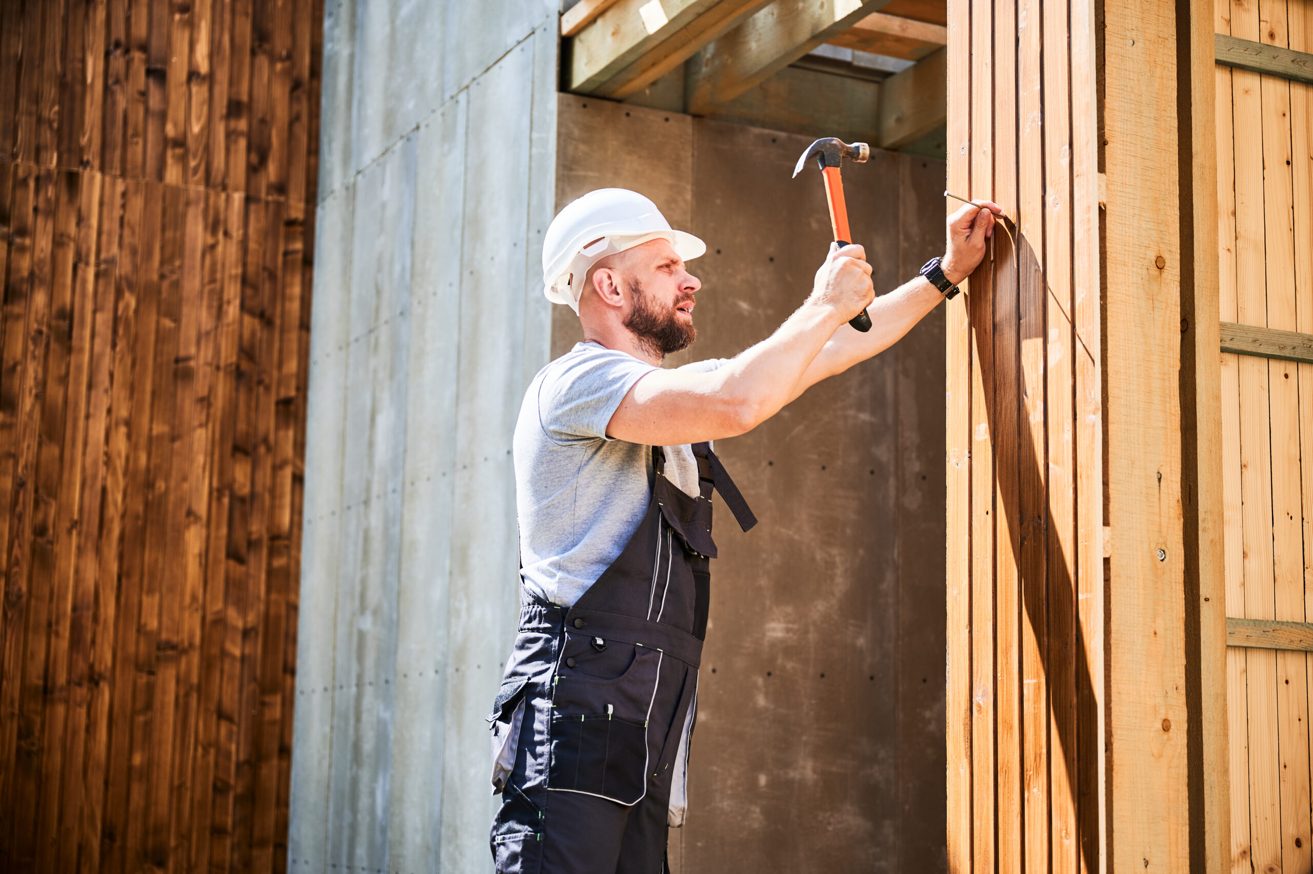 carpenter hammering nail while constructing wooden scaled